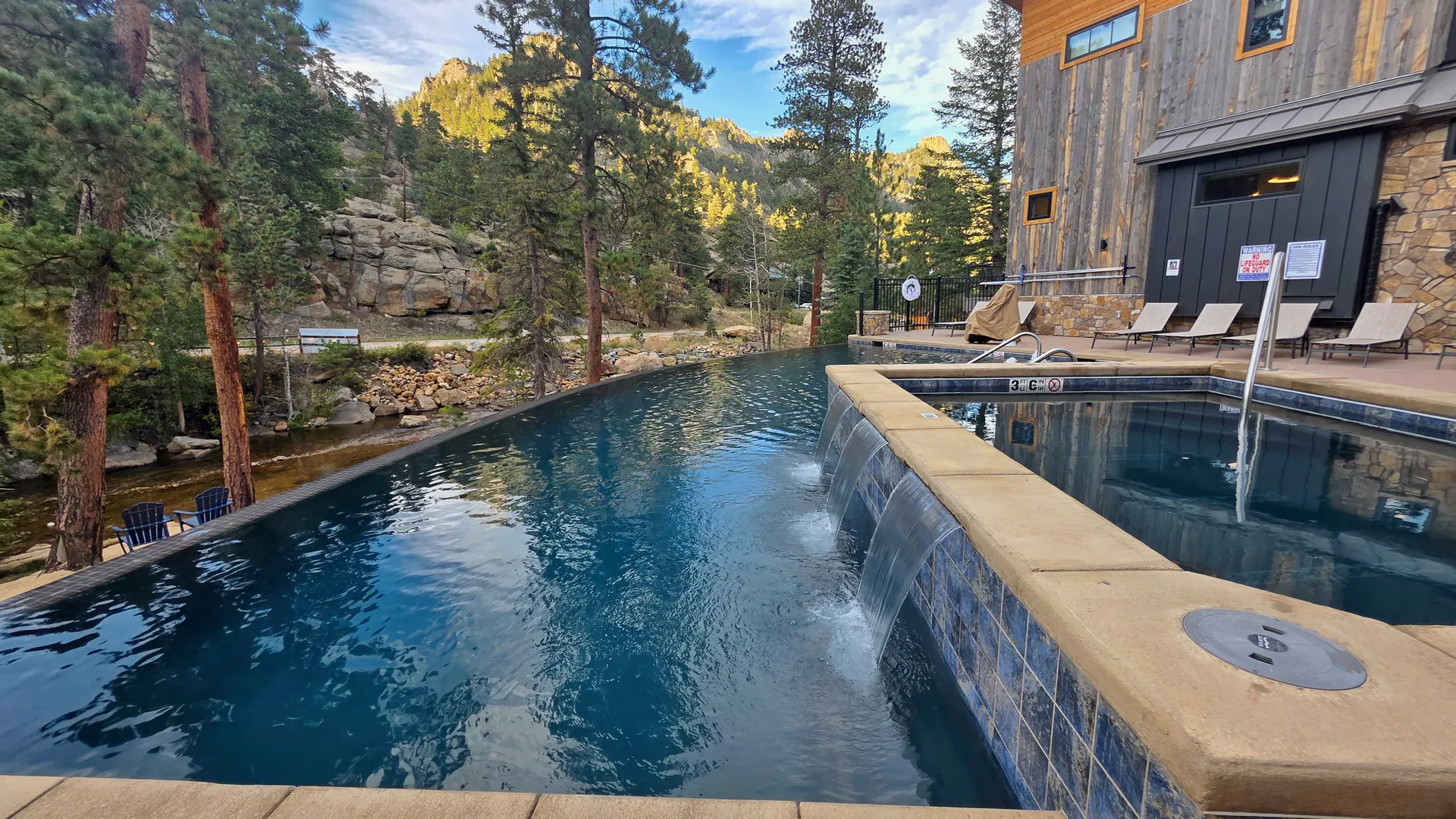 The shared DreamView infinity pool beside Fall River, with pines and mountains beyond