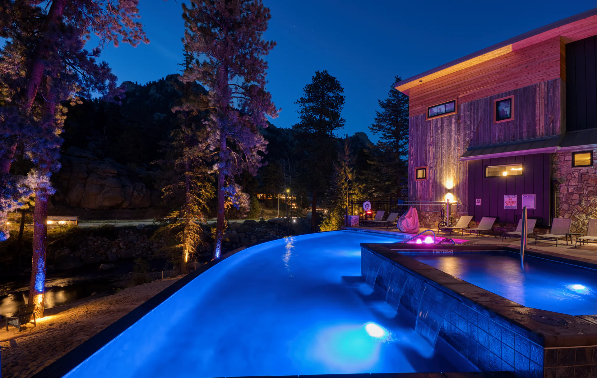 The shared DreamView infinity pool glowing blue at dusk beside Fall River