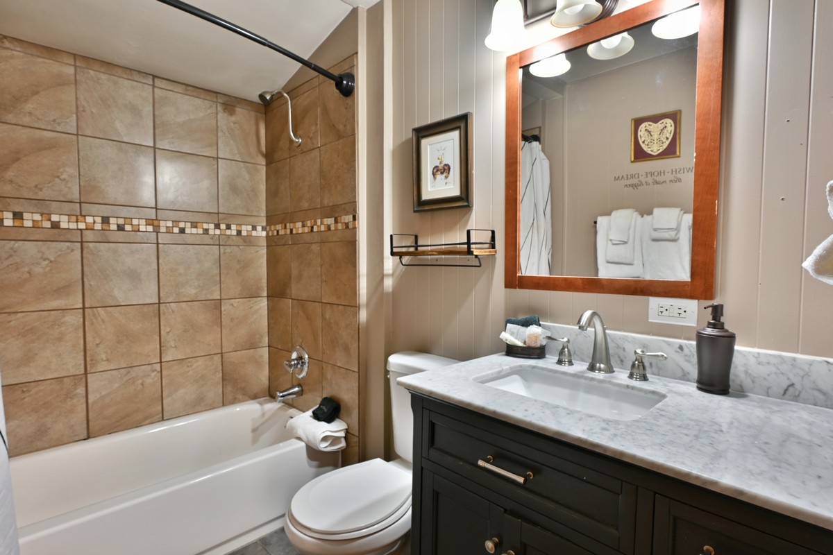 A clean bathroom with a bathtub, toilet, and marble countertop