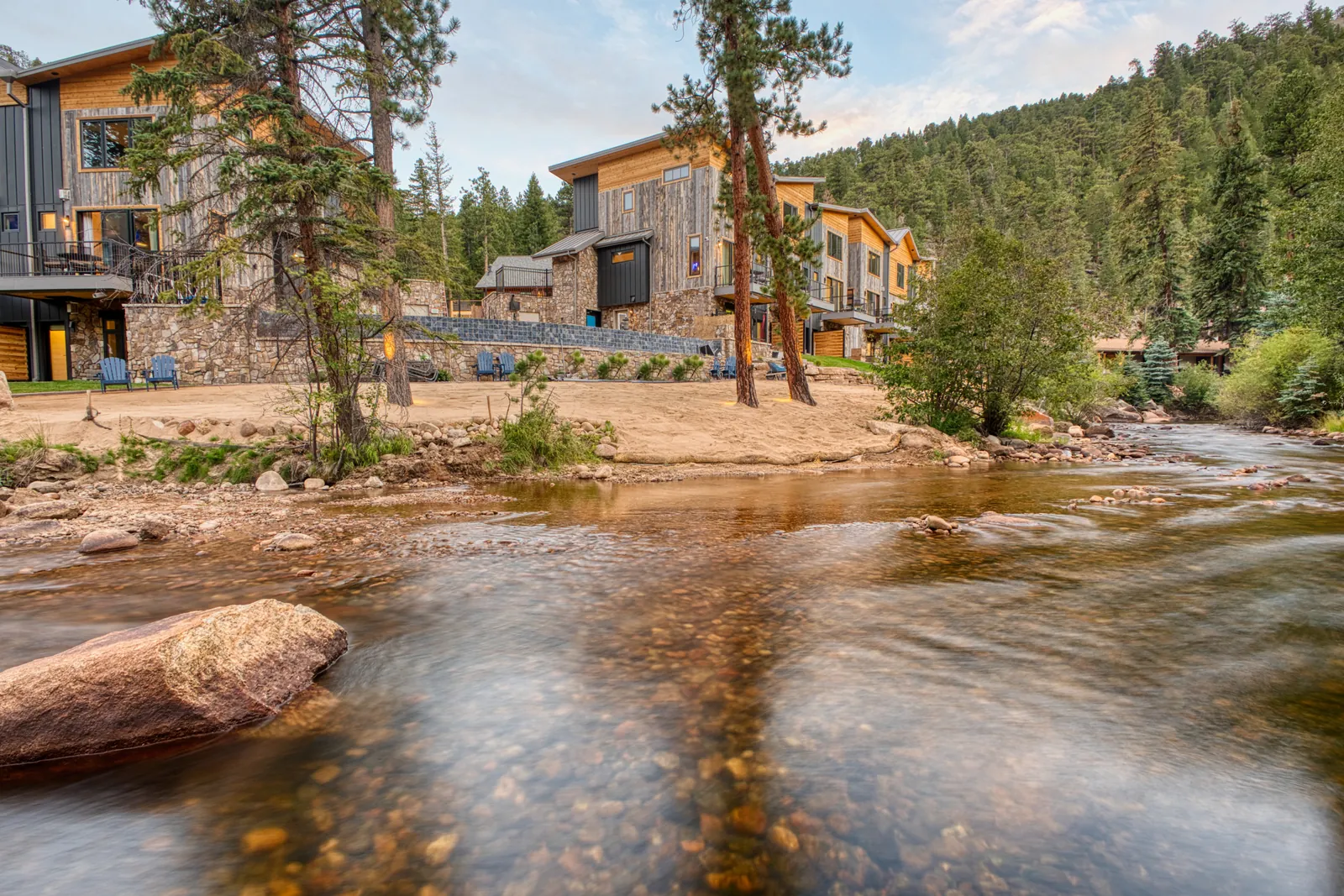DreamView suites beside Fall River, with pine trees and flowing water in Estes Park, Colorado
